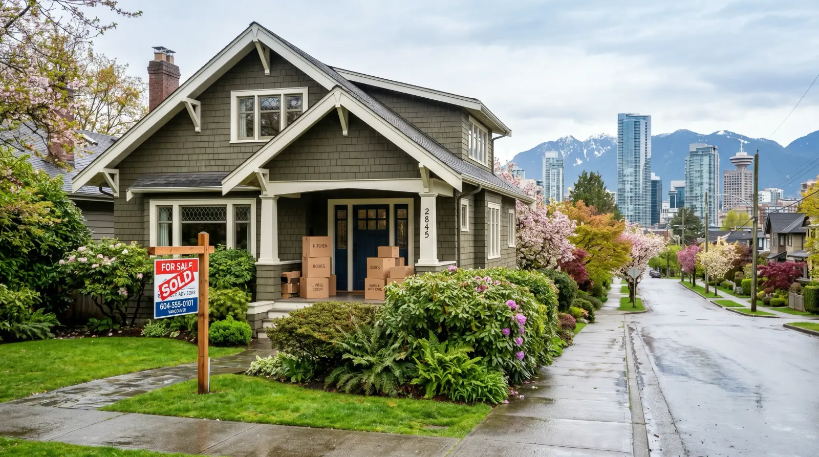 Vancouver craftsman house with a SOLD sign and moving boxes on the porch, downtown condo towers and North Shore mountains in the distance