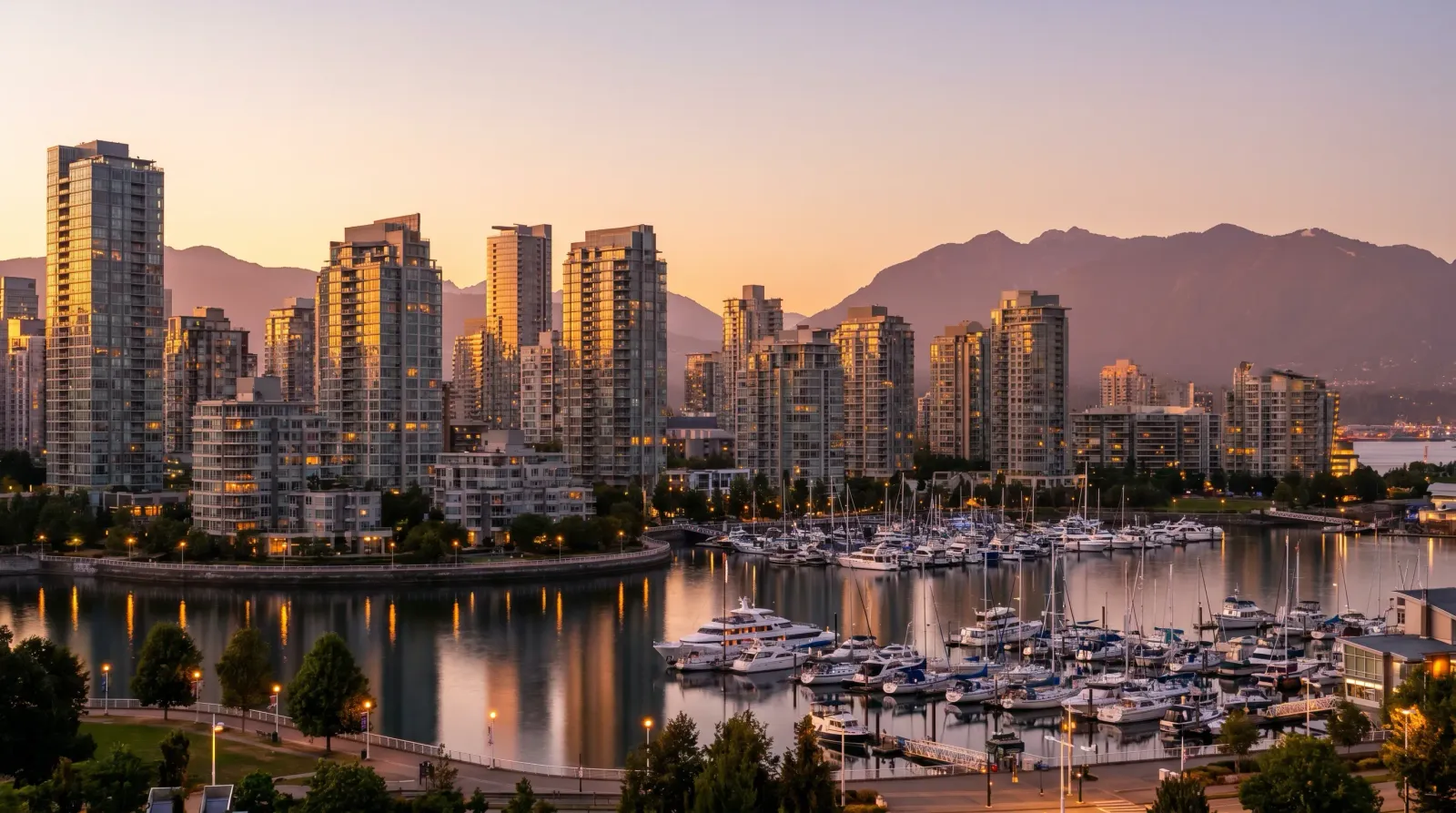 Vancouver Yaletown waterfront condo towers at dusk reflecting amber sunset light over False Creek marina
